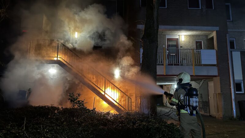 Brandweer blust brandende container onder trap in Leeuwarden