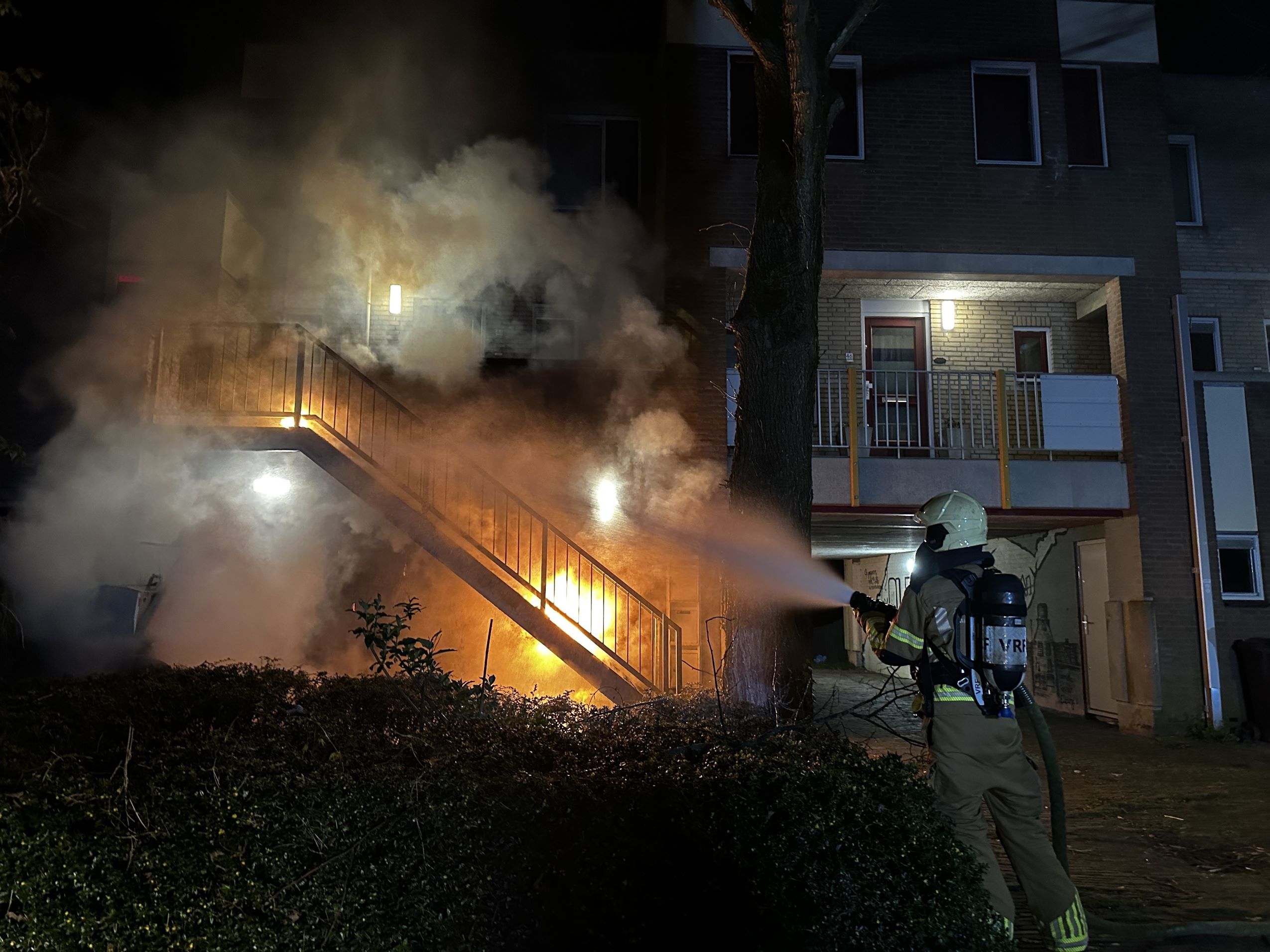Brandweer blust brandende container onder trap in Leeuwarden