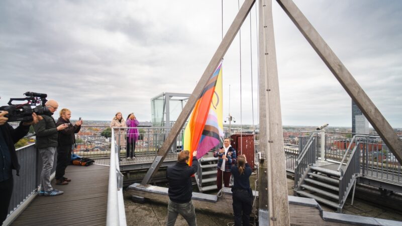 Wethouder Kuiken en Nils van Mourik (COC) hijsen regenboogvlag op de Oldehove