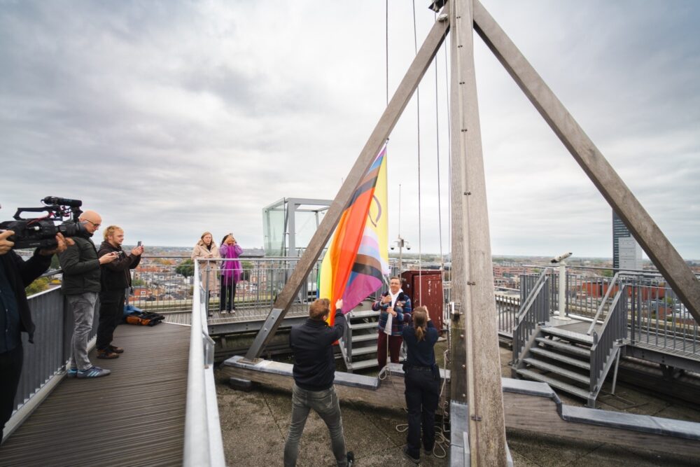 Wethouder Kuiken en Nils van Mourik (COC) hijsen regenboogvlag op de Oldehove