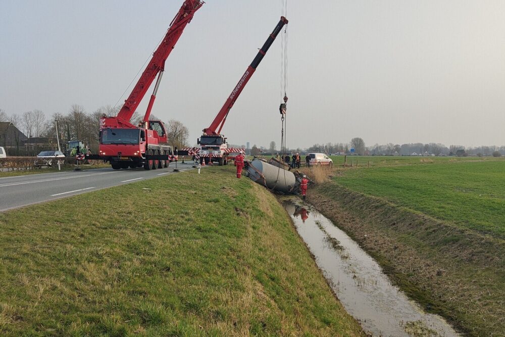 Twee kranen takelen giertank uit de sloot bij Jelsum